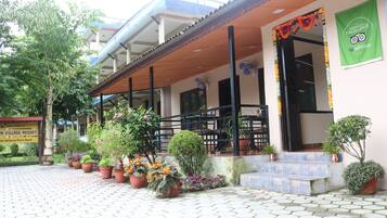 A resort entrance with potted plants, a signboard, and a green banner.