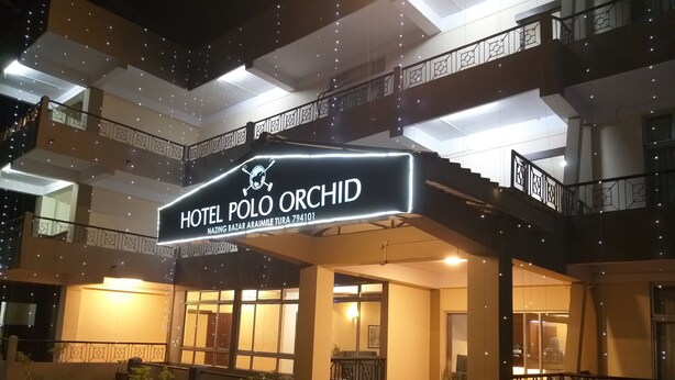 A hotel entrance with a sign reading "Hotel Polo Orchid" and a visible address. - Polo Tura Hotel (West Garo Hills)