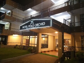 Entrada de hotel com uma placa indicando 'Hotel Polo Orchid' e o endereço visível.