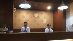 A reception desk with two staff members, a clock, and a framed certificate on the wall. - Polo Tura Hotel (West Garo Hills)
