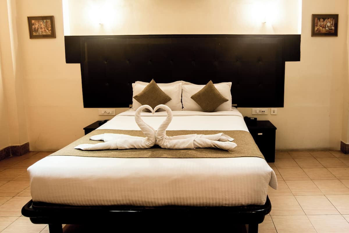 A hotel room with a neatly made bed, a black headboard, and two nightstands with lamps.