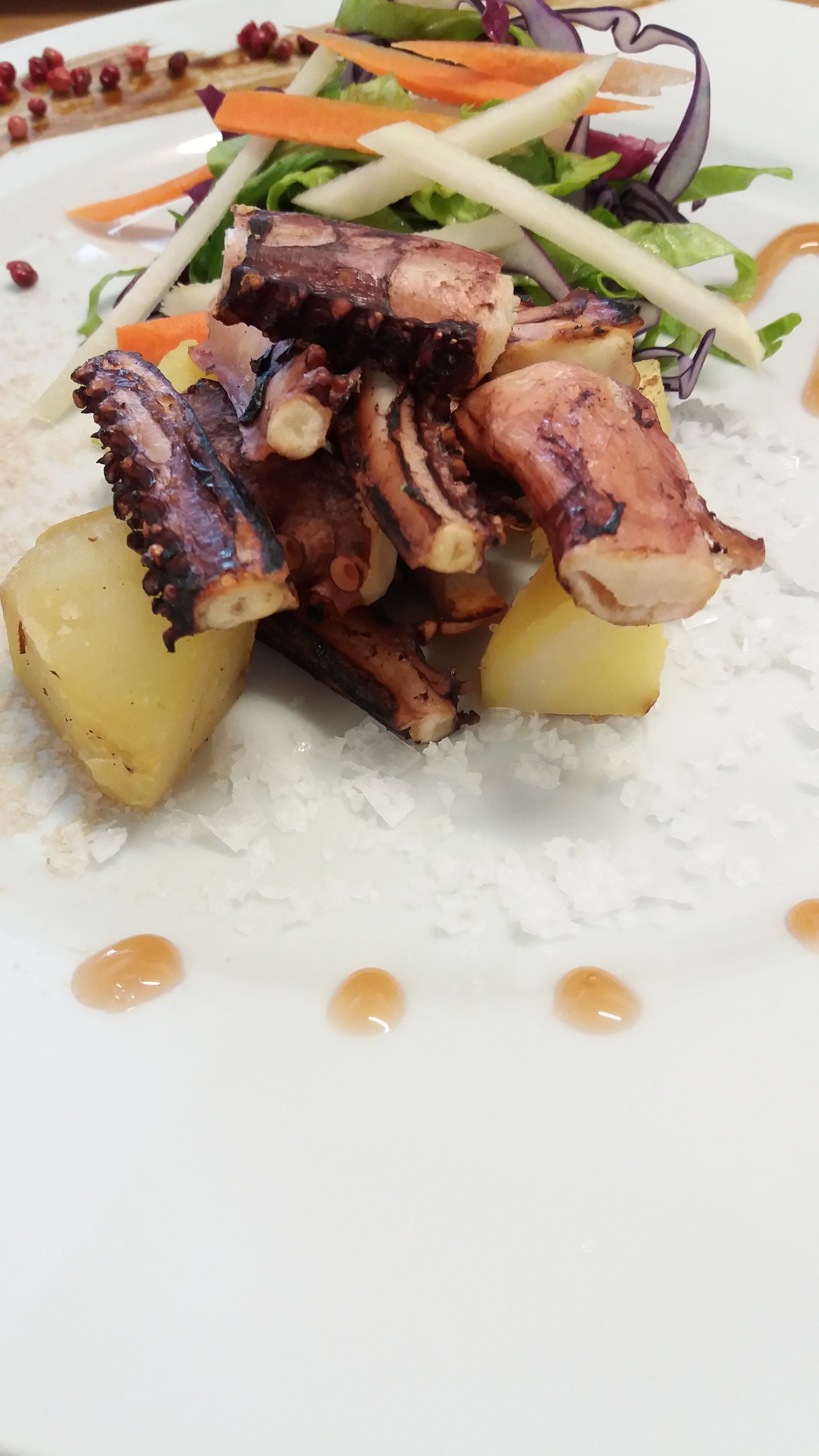Une assiette de poulpe, de pommes de terre et une salade.