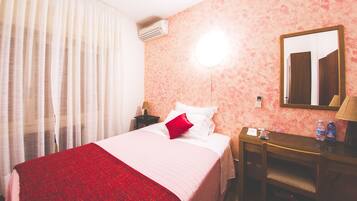Une chambre d’hôtel équipée d’un lit, d’un bureau, d’un miroir et d’un appareil de climatisation.