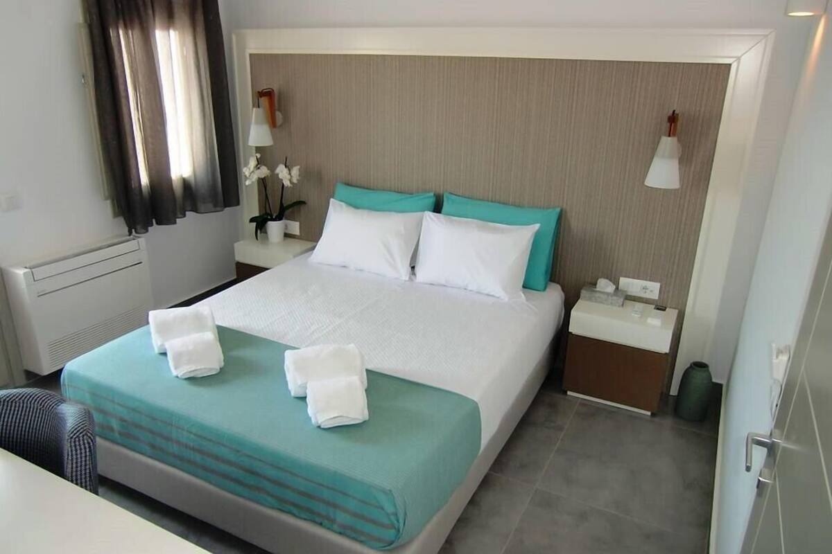 A hotel room with a bed, a nightstand, a lamp, and a vase with flowers.