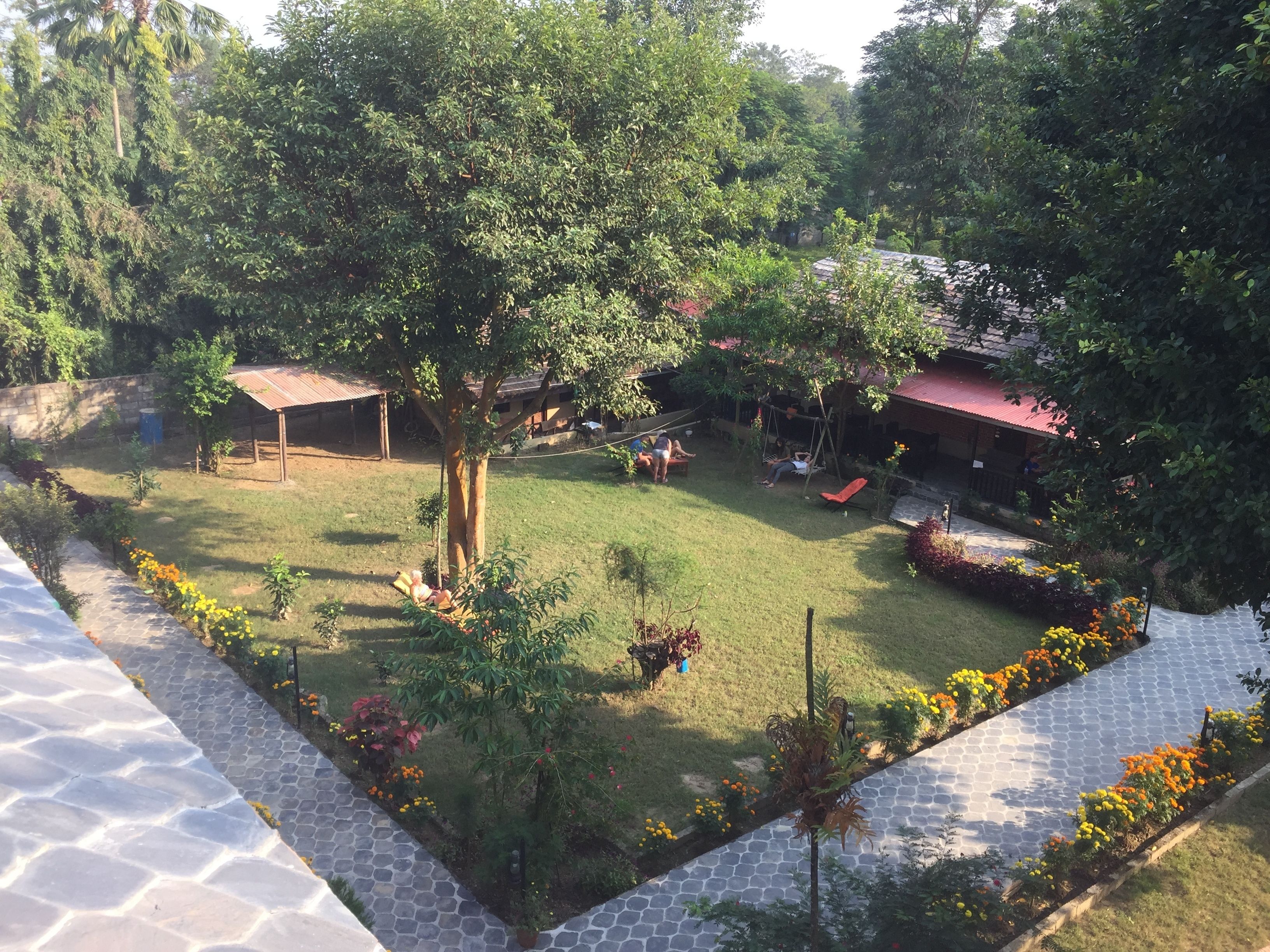 Un patio con un columpio, una zona de estar techada y un pequeño jardín con flores.