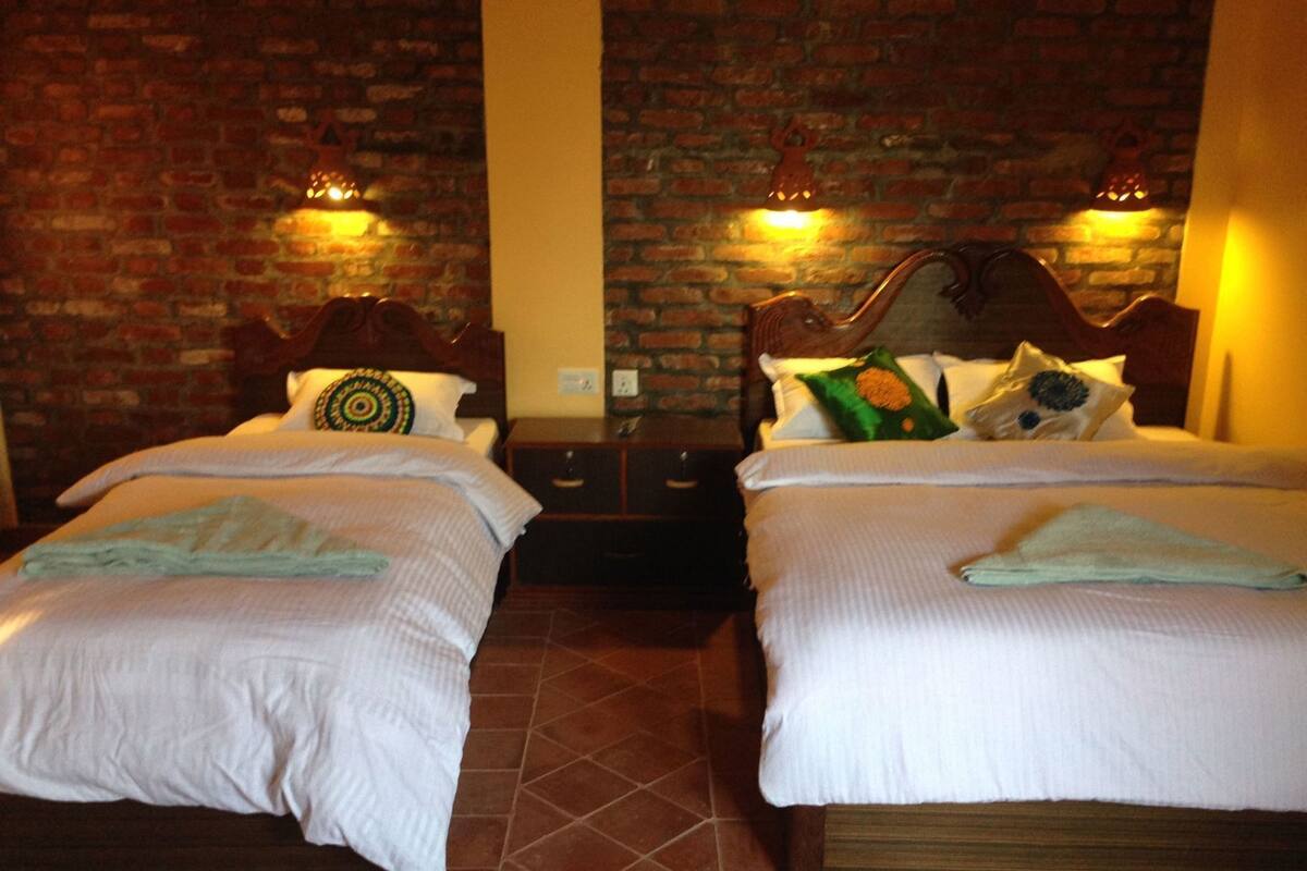Une chambre avec deux lits, un mur en briques et une tête de lit en bois.