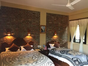 A room with two beds, brick walls, and a ceiling fan. - Chautari Garden Resort (Sauraha)