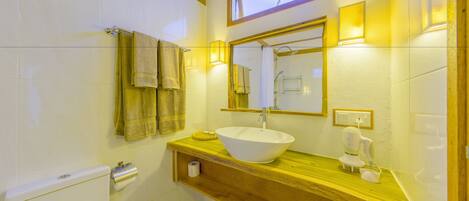 A bathroom with a wooden vanity, a white sink, and a mirror above it. There are towels hanging on the wall and a toilet visible to the left.