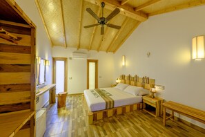 A wooden-floored bedroom with a bed, bedside tables, and a ceiling fan. - Ameera Maldives (Dhiffushi)