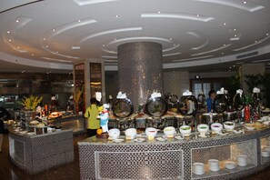 A buffet area with a circular central feature, multiple food stations, and a modern ceiling design.