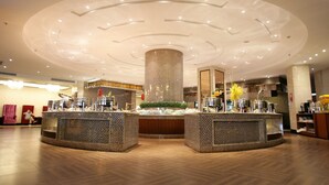 A modern hotel lobby with a central column, a round bar area, and a herringbone wooden floor. - Huilihua Hotel (Dongguan)