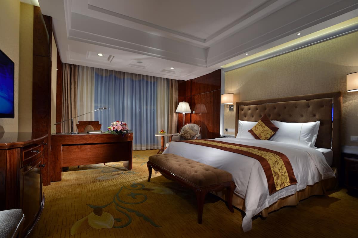 Habitación de hotel con una cama grande, un escritorio, una silla y un televisor.