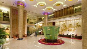 A spacious lobby with a central aquarium, a staircase, and a reception desk. - Huilihua Hotel (Dongguan)