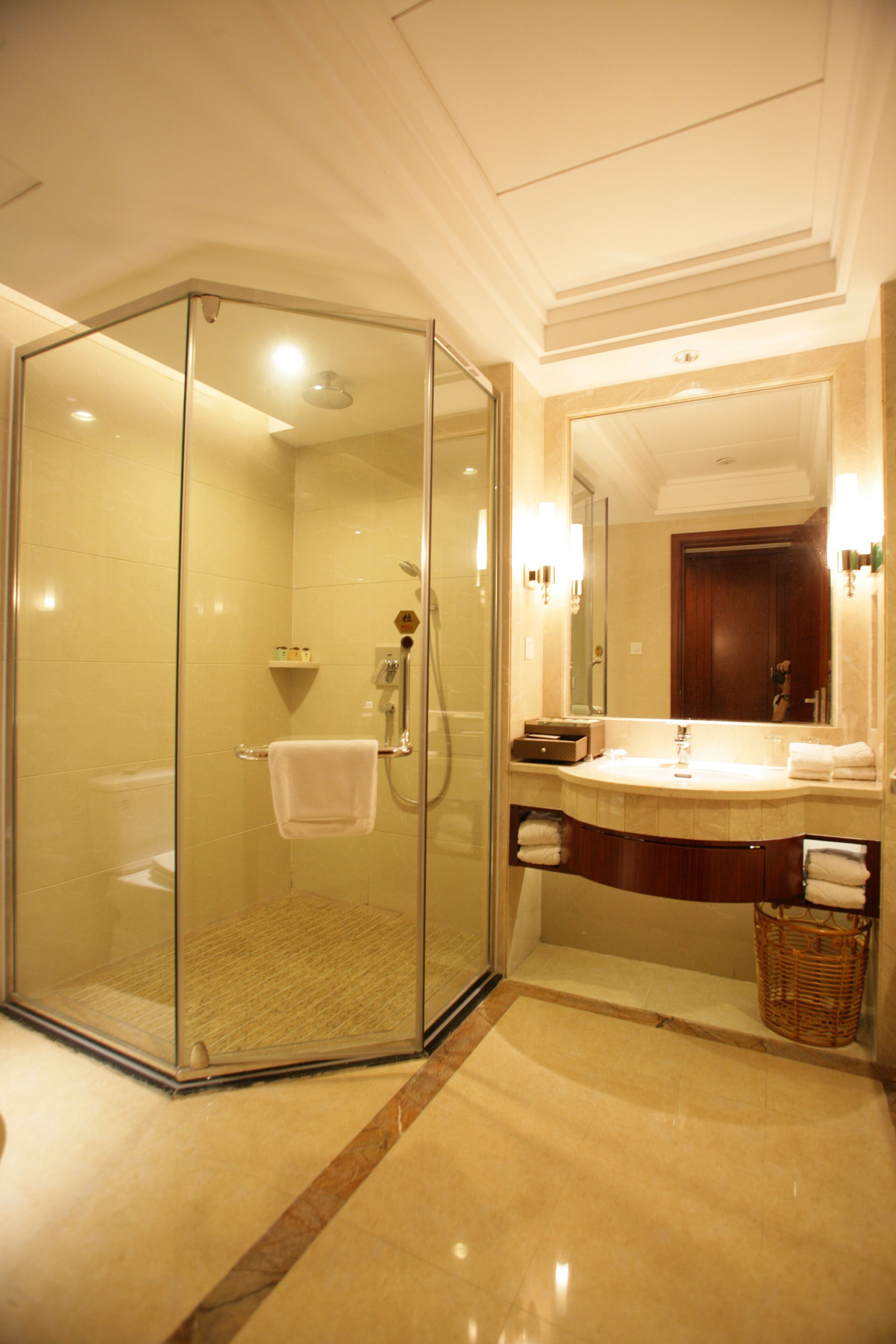 A modern bathroom with a glass-enclosed shower, a vanity with a mirror, and a marble floor.