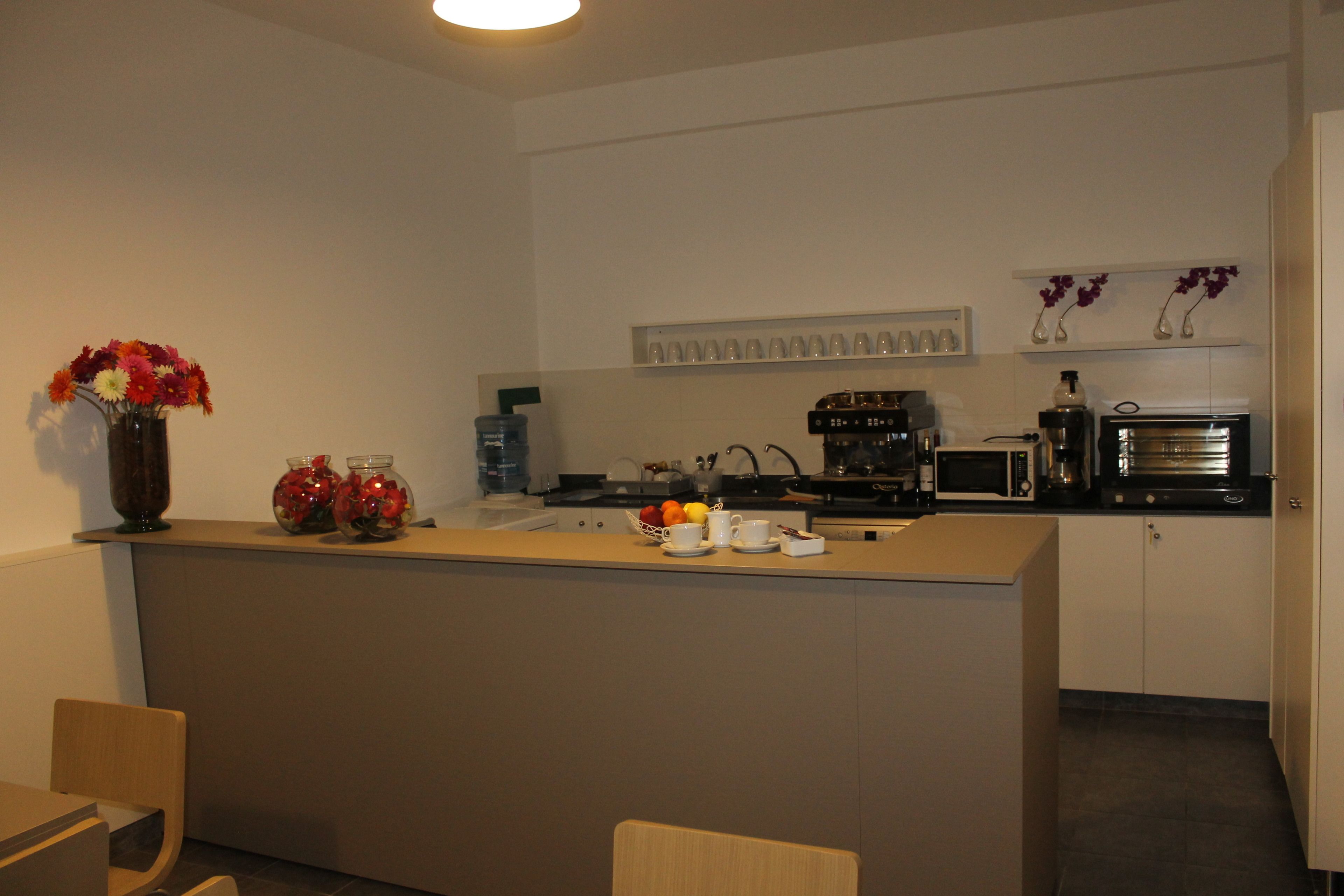Eine moderne Küche mit einer zentralen Kochinsel, einer Mikrowelle, einer Kaffeemaschine und einem Blumenarrangement auf der Arbeitsplatte.