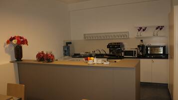 Eine moderne Küche mit einer zentralen Kochinsel, einer Mikrowelle, einer Kaffeemaschine und einem Blumenarrangement auf der Arbeitsplatte.