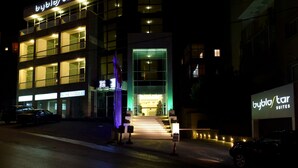 Ett hotell med en modern fasad, flera balkonger och upplyst skyltning.