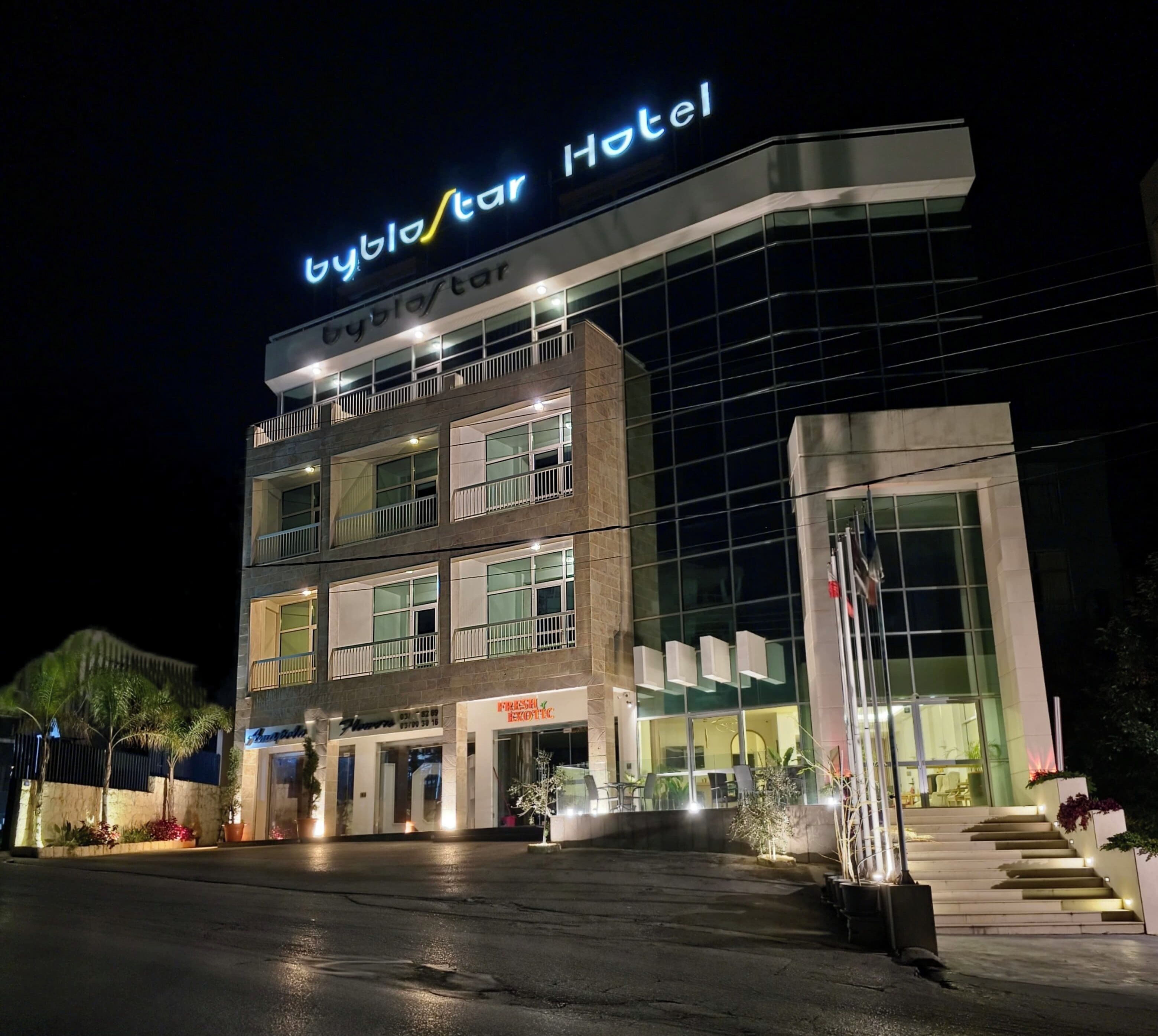 A modern hotel with a prominent 'Byblos Hotel' sign, multiple floors, and a well-lit entrance.