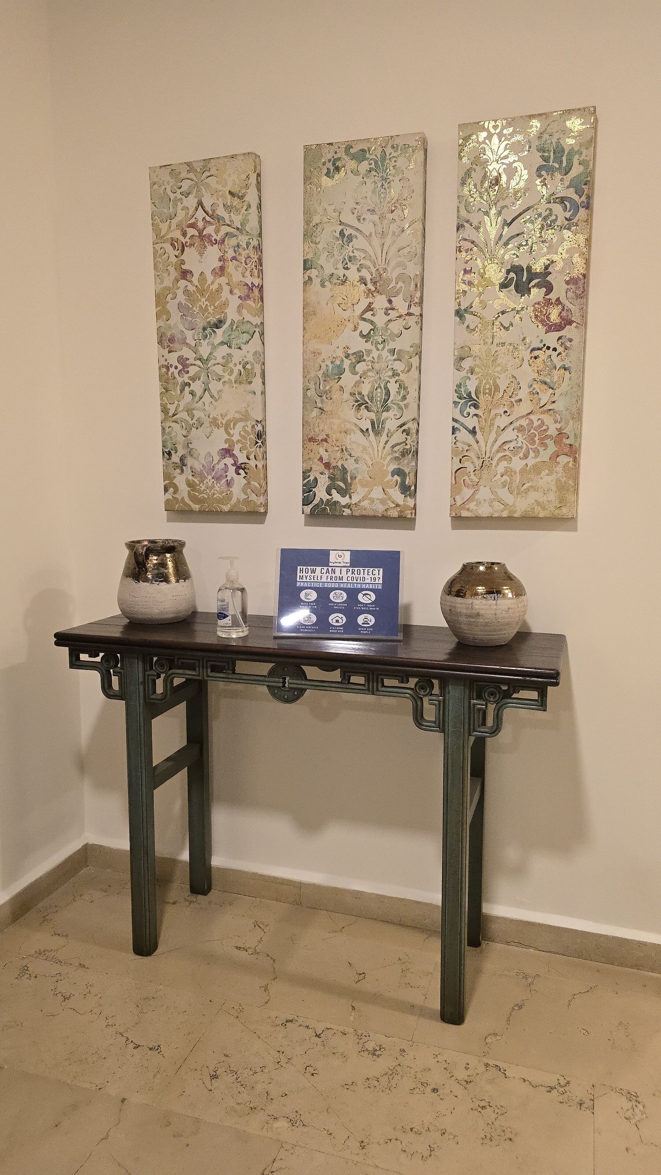Une table ornée de vases décoratifs et d’un panneau indiquant les consignes de sécurité sanitaire.