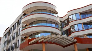 Experience the sleek, modern design of this multi-story building with curved balconies and a bold, contemporary facade.