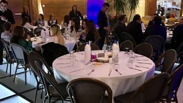 Un restaurant avec des tables rondes, des chaises et un serveur.