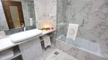 Un baño con lavamanos de mármol, ducha con cerramiento de vidrio y bañera.