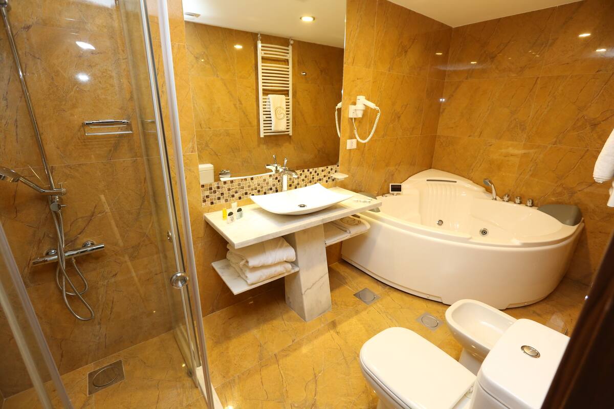 Une salle de bain moderne dotée d’une douche à parois de verre, d’une baignoire sur pied et d’un meuble-lavabo avec un évier et un miroir.