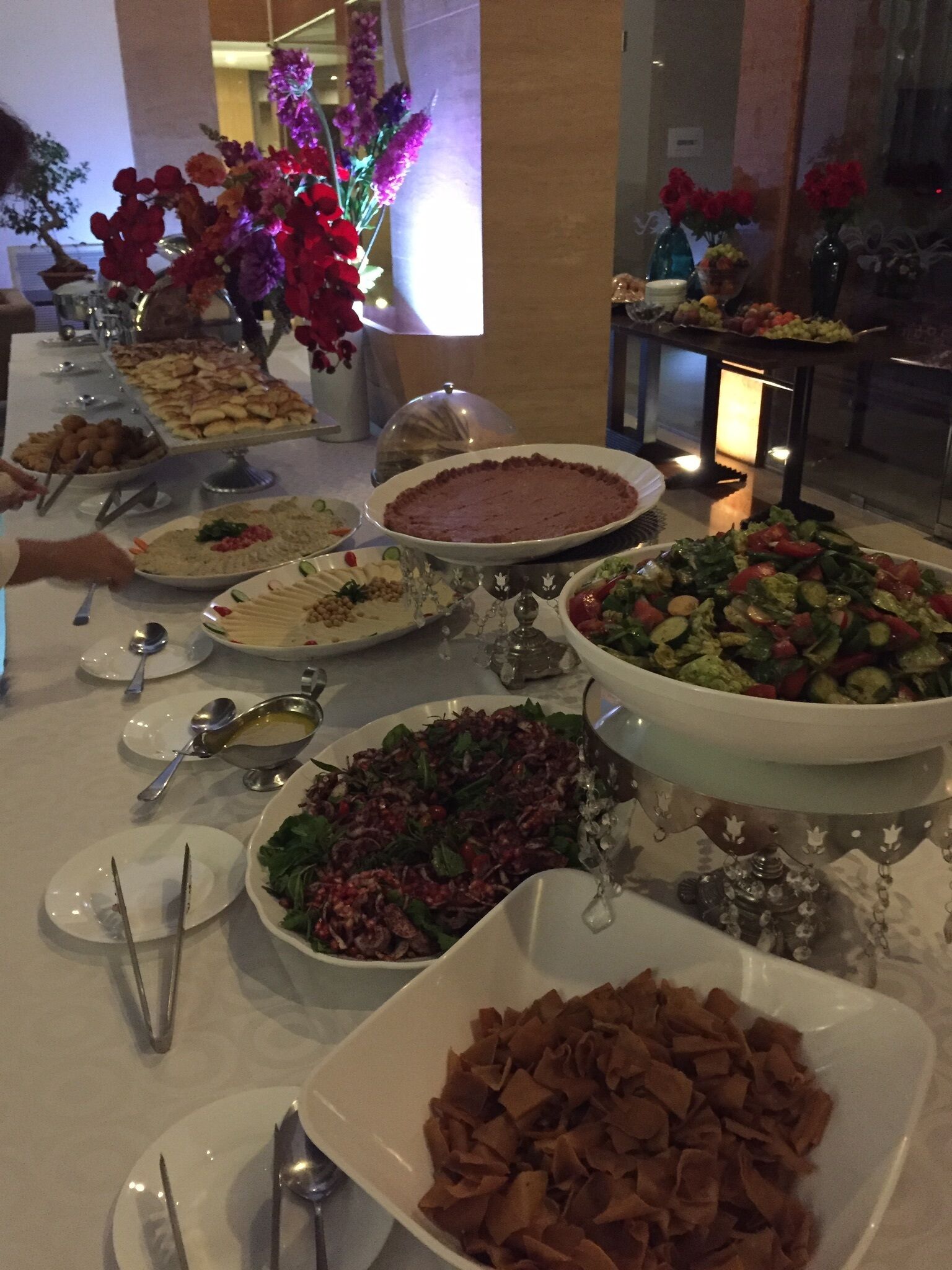 A buffet table with various dishes, including salads, desserts, and a large pie.