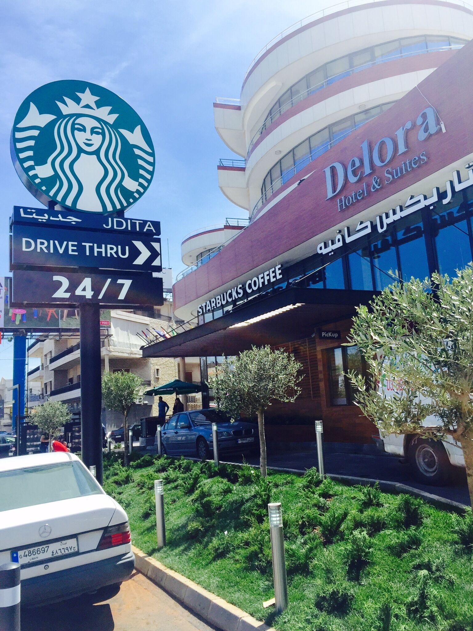 A hotel with a Starbucks Coffee sign, a drive-thru, and a sign indicating 24/7 service.