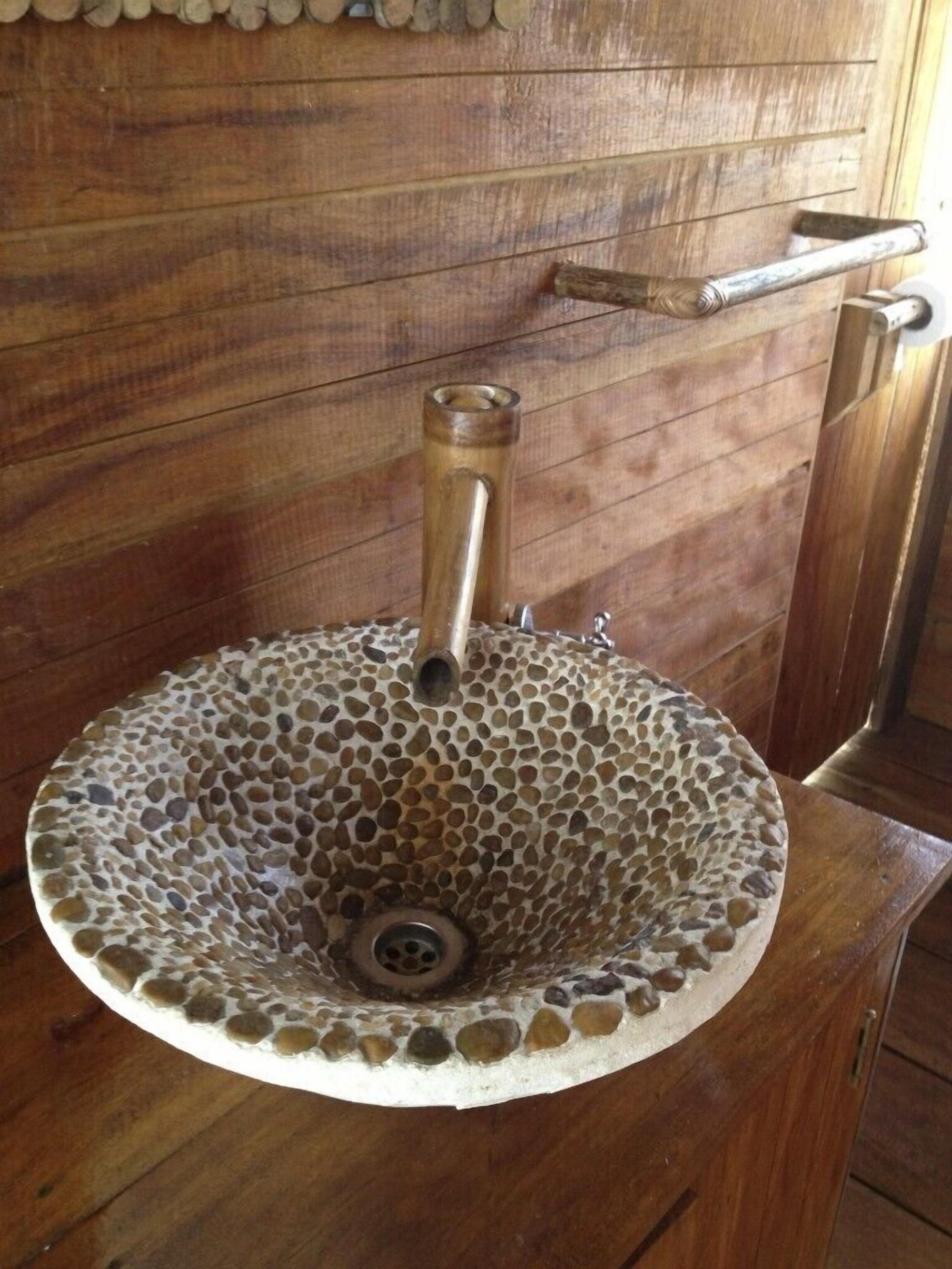 A round sink with a mosaic design, mounted on a wooden wall.