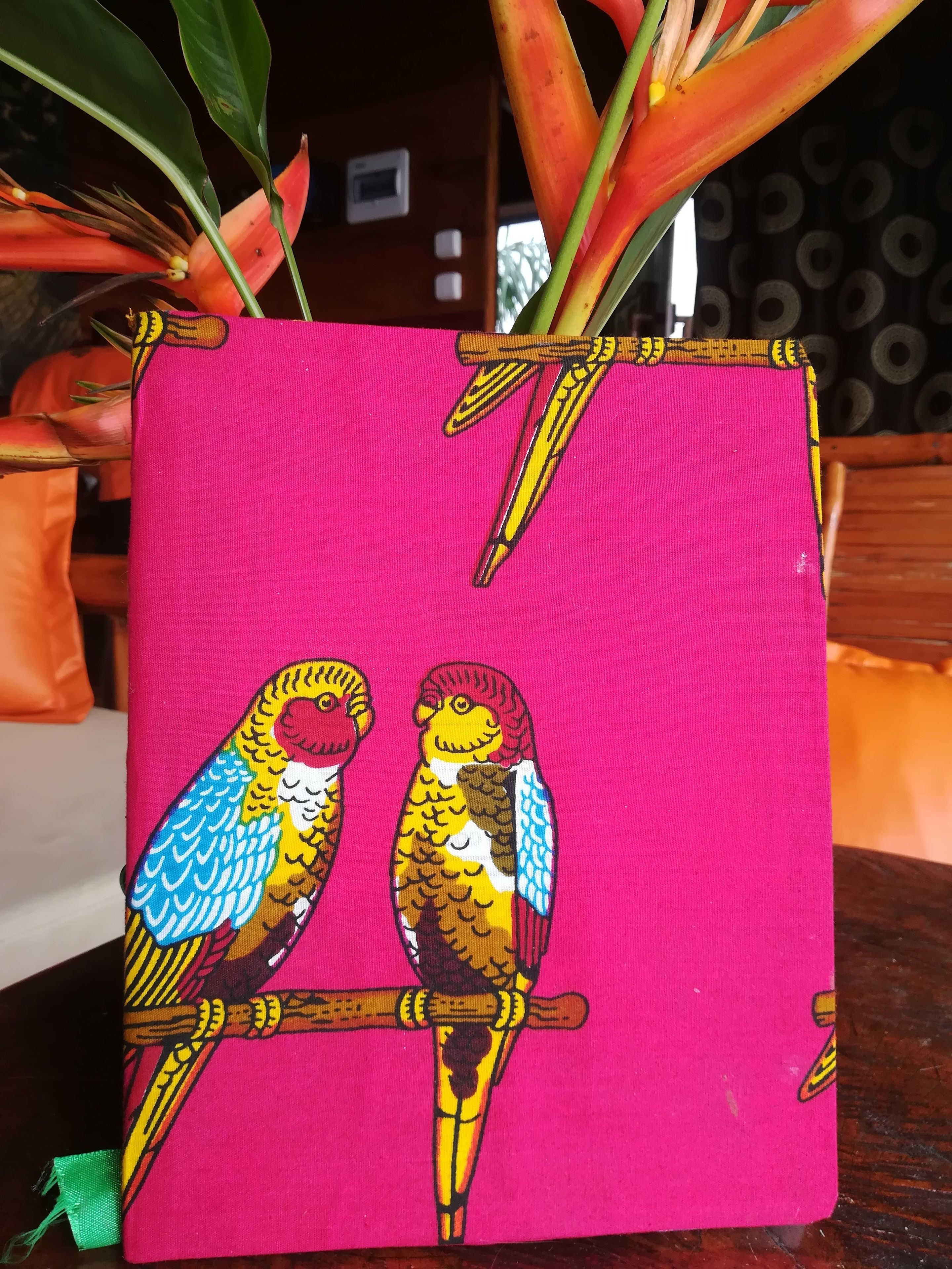 A vibrant pink fabric with a colorful bird design, likely a decorative item or artwork.