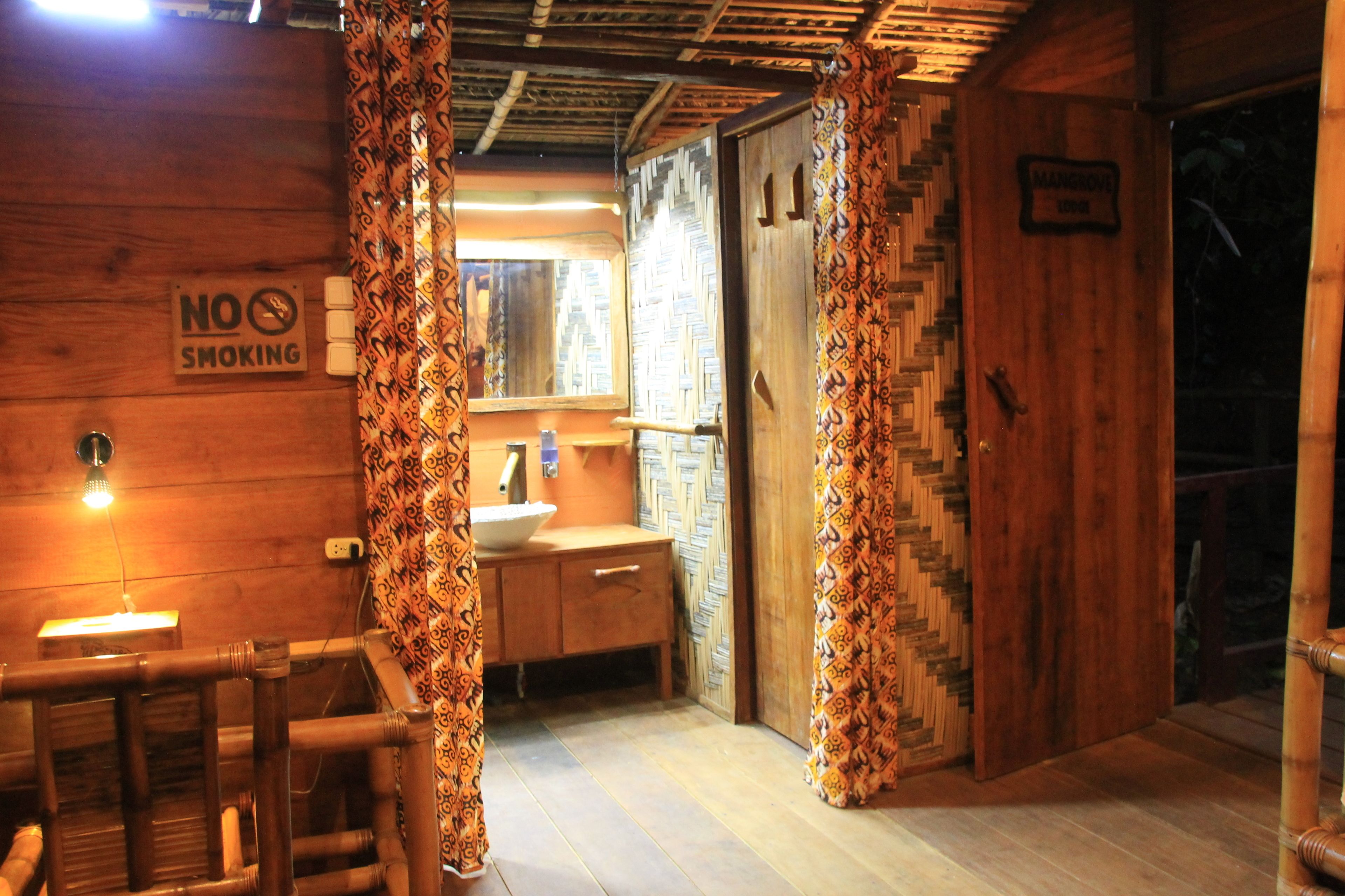 Interieur van een houten chalet met een houten bankje, een wastafel en een bordje 'Niet roken'.