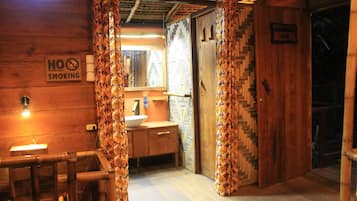 Interieur van een houten chalet met een houten bankje, een wastafel en een bordje 'Niet roken'.