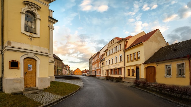 A street with historic buildings, a cobblestone path, and a sign reading "Pension Panstky Dum."