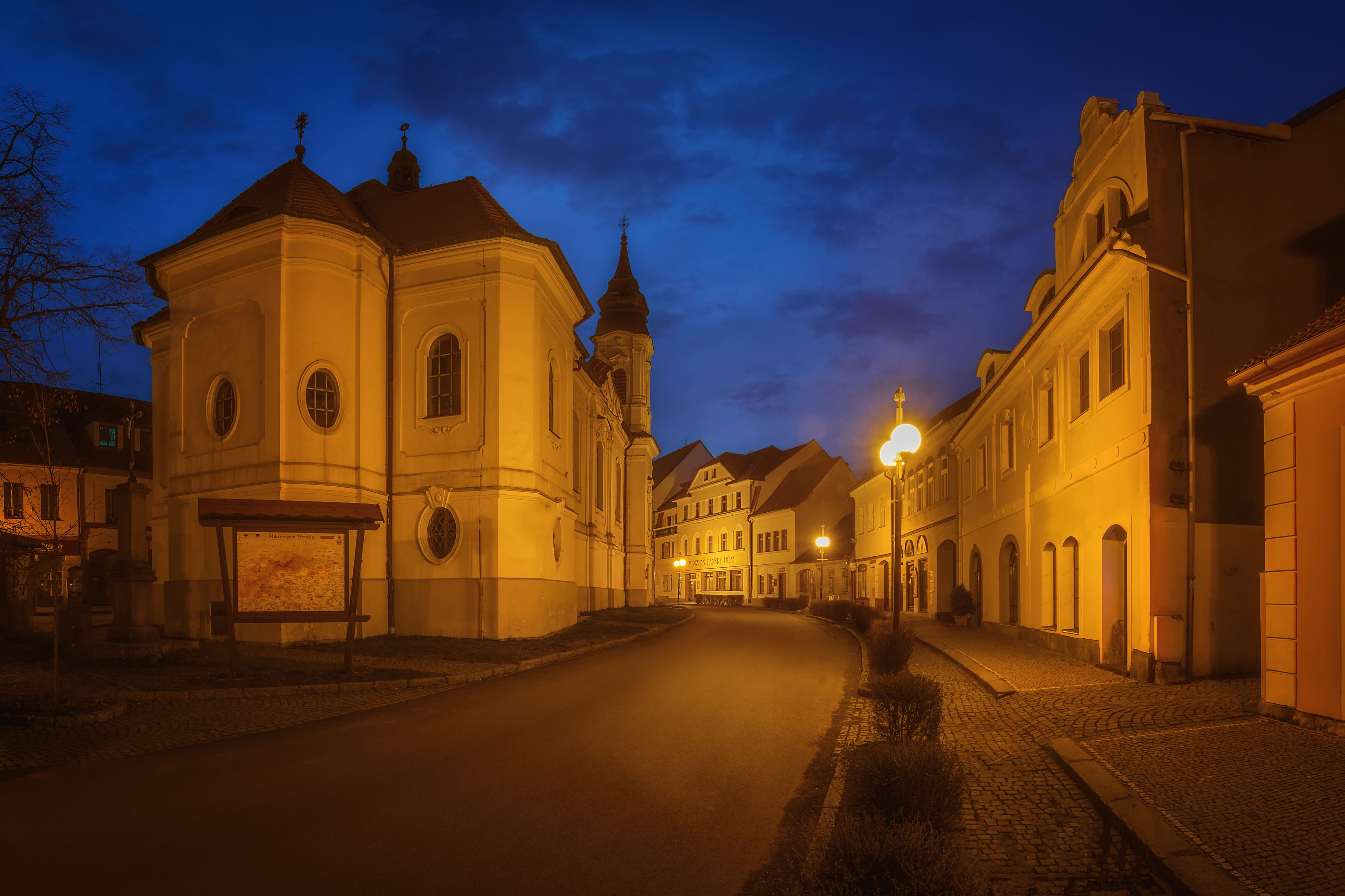 Een historische straat met traditionele architectuur, een kerk en geplaveid voetpad.
