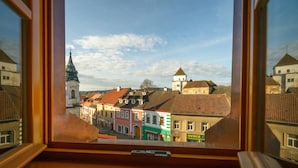 A view from a window of a town with colorful buildings, a church steeple, and a tower.