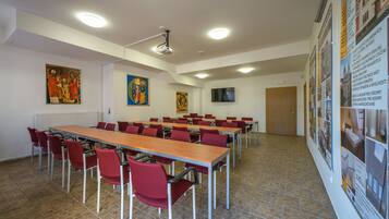 A conference room with a long table, red chairs, a projector, and informational posters on the walls.