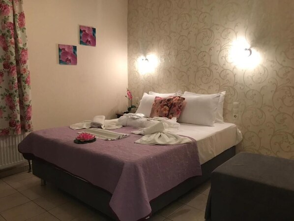 Un dormitorio con una cama, una mesita de noche y otra mesilla auxiliar.