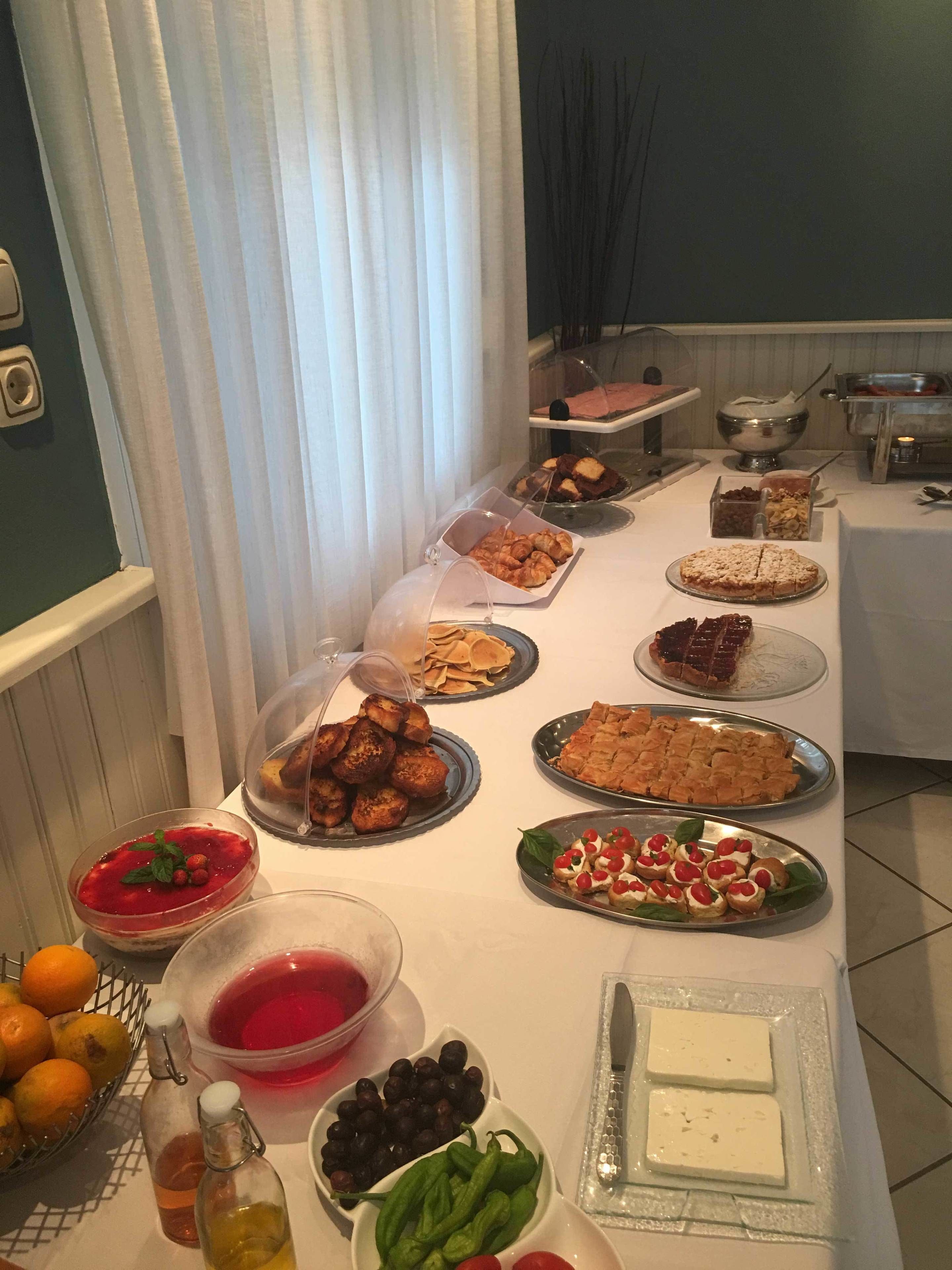 Una mesa de buffet con diversos alimentos, como pasteles, postres y frutas.