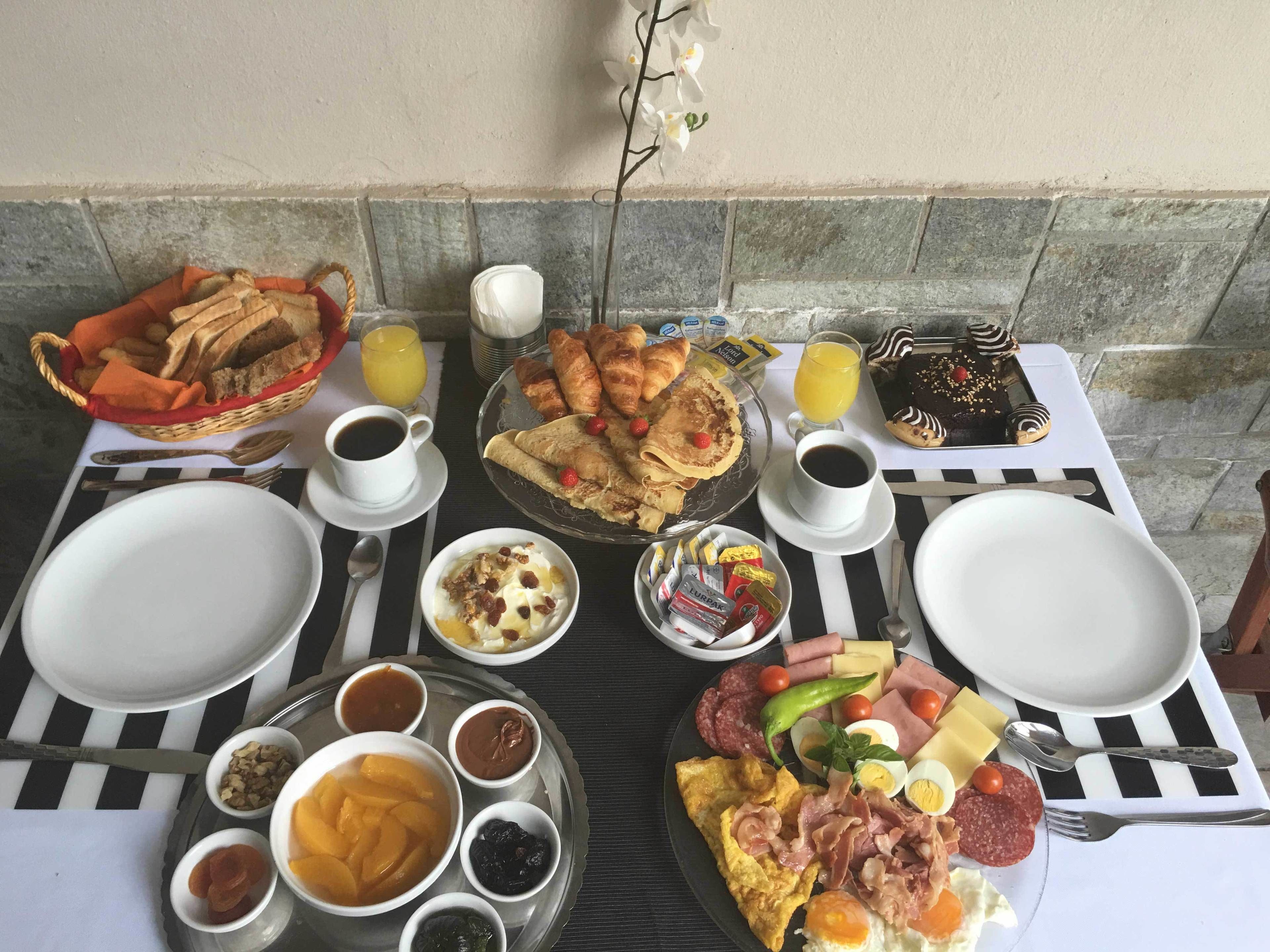 Un buffet de petit-déjeuner avec divers plats, boissons et ustensiles disposés sur une table.