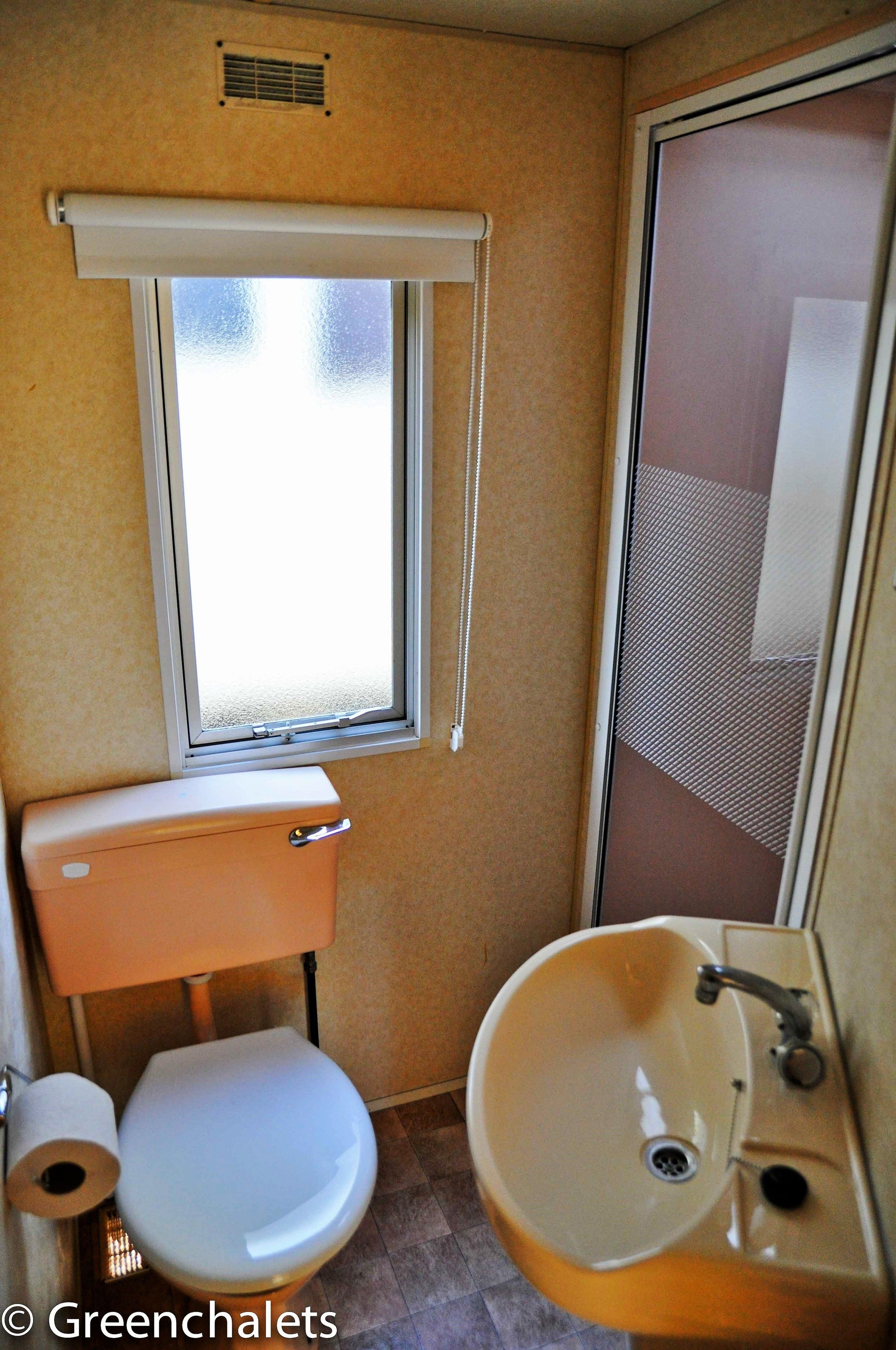 Ein kleines Badezimmer mit Toilette, Waschbecken und Fenster.