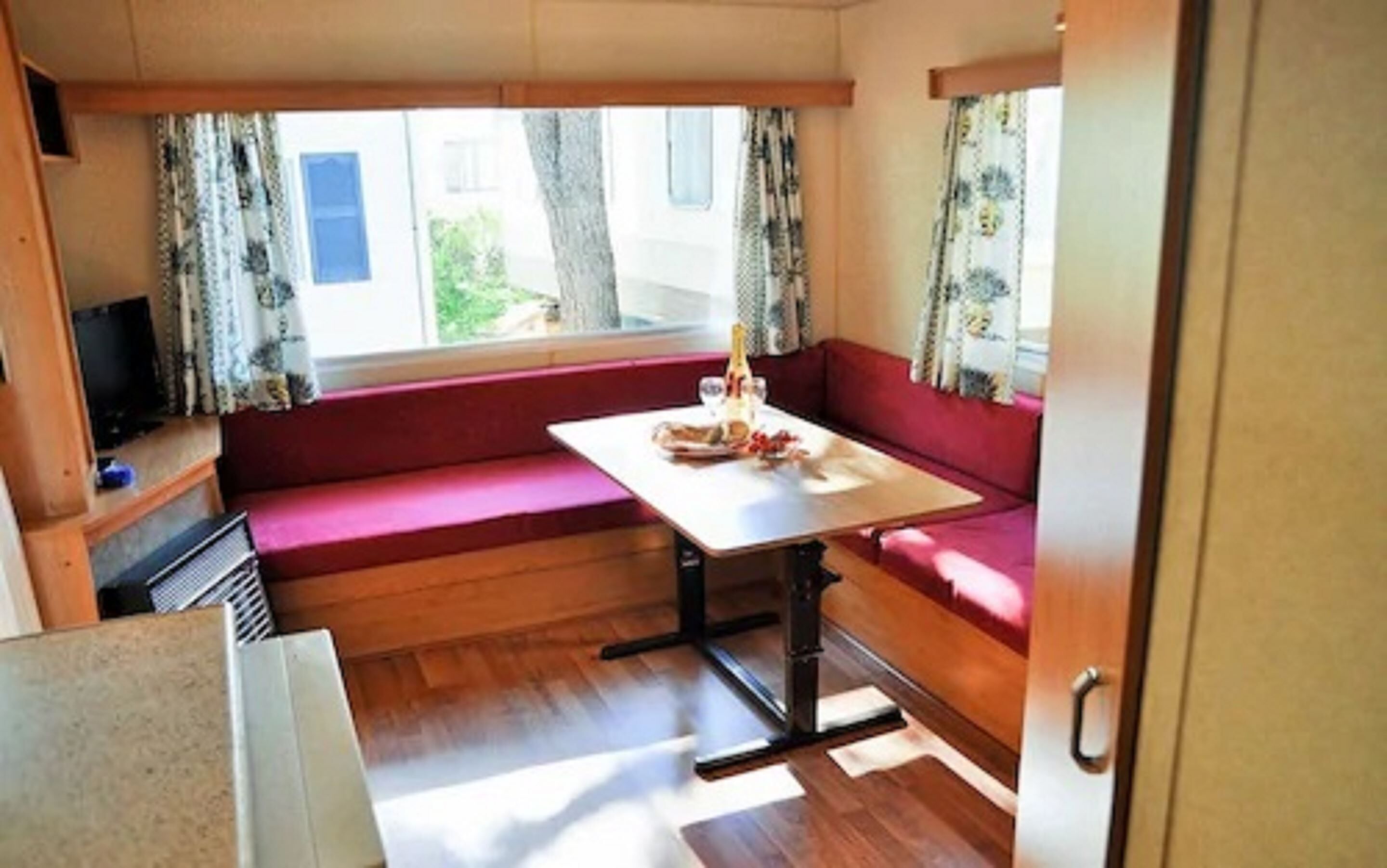 Ett kompakt inre utrymme i husbilen med en matplats, sittplatser och en tv.