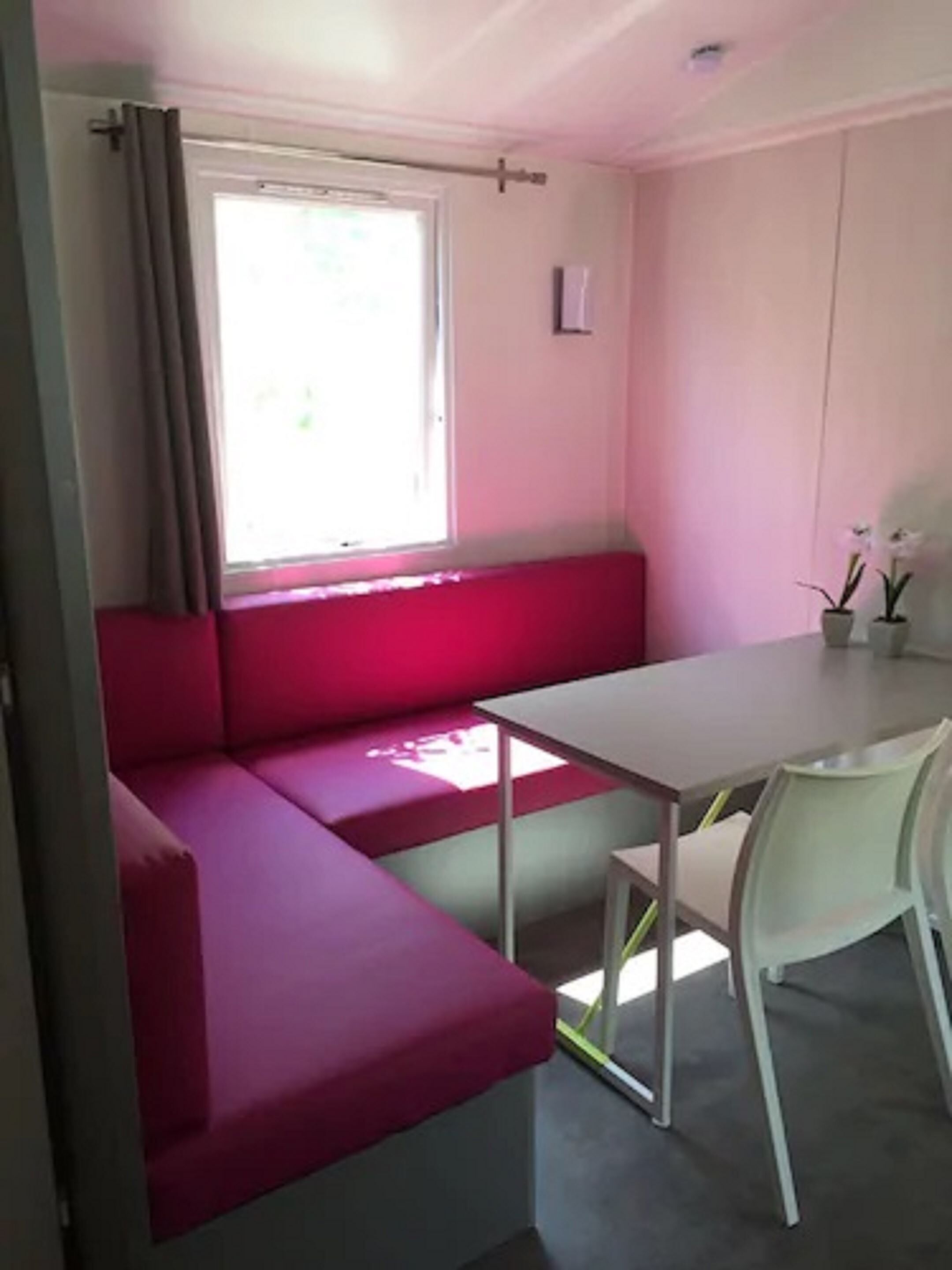Una habitación con un sofá rojo, una mesa y sillas.