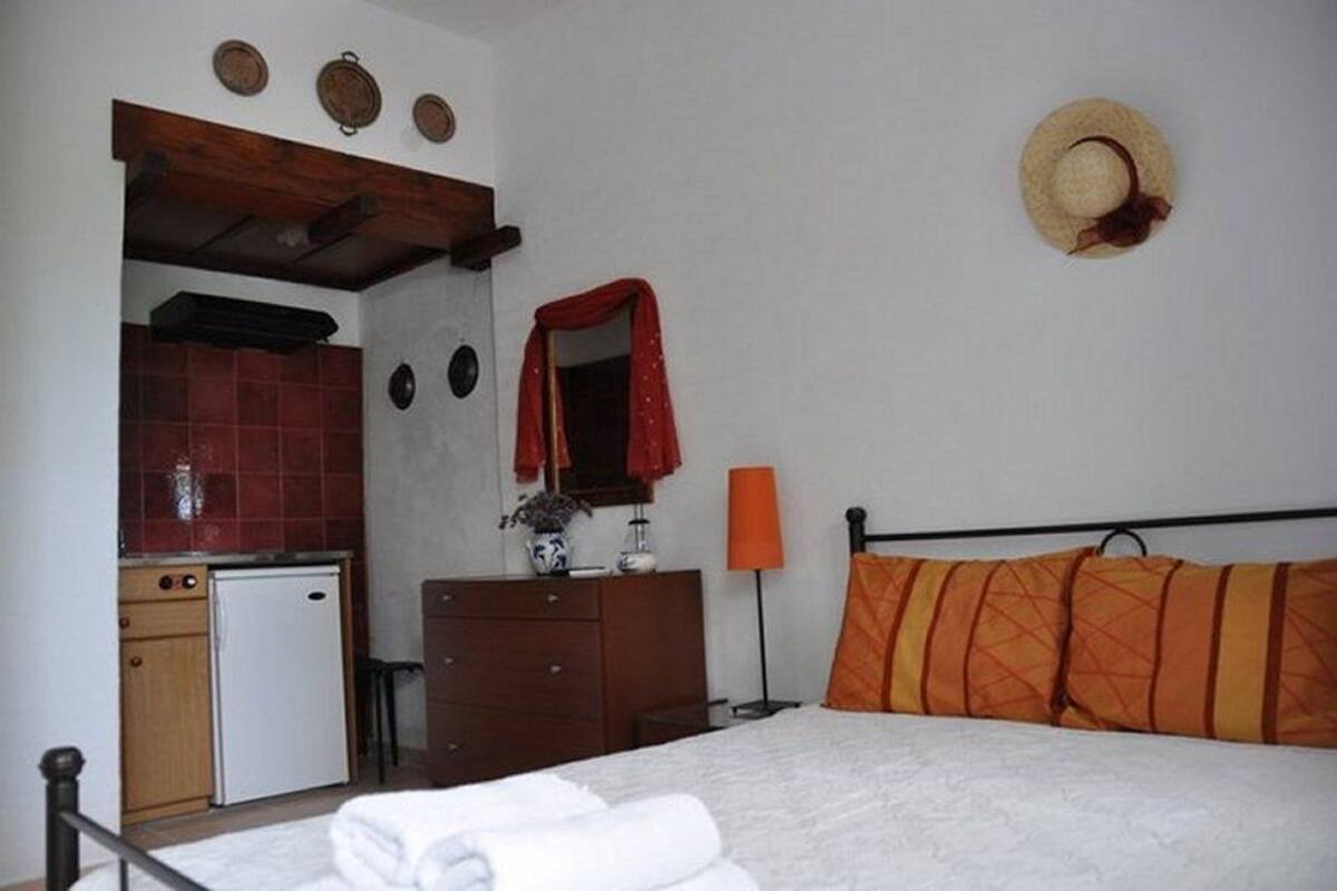 Un dormitorio con cama, cómoda, espejo, lámpara y una pequeña kitchenette.