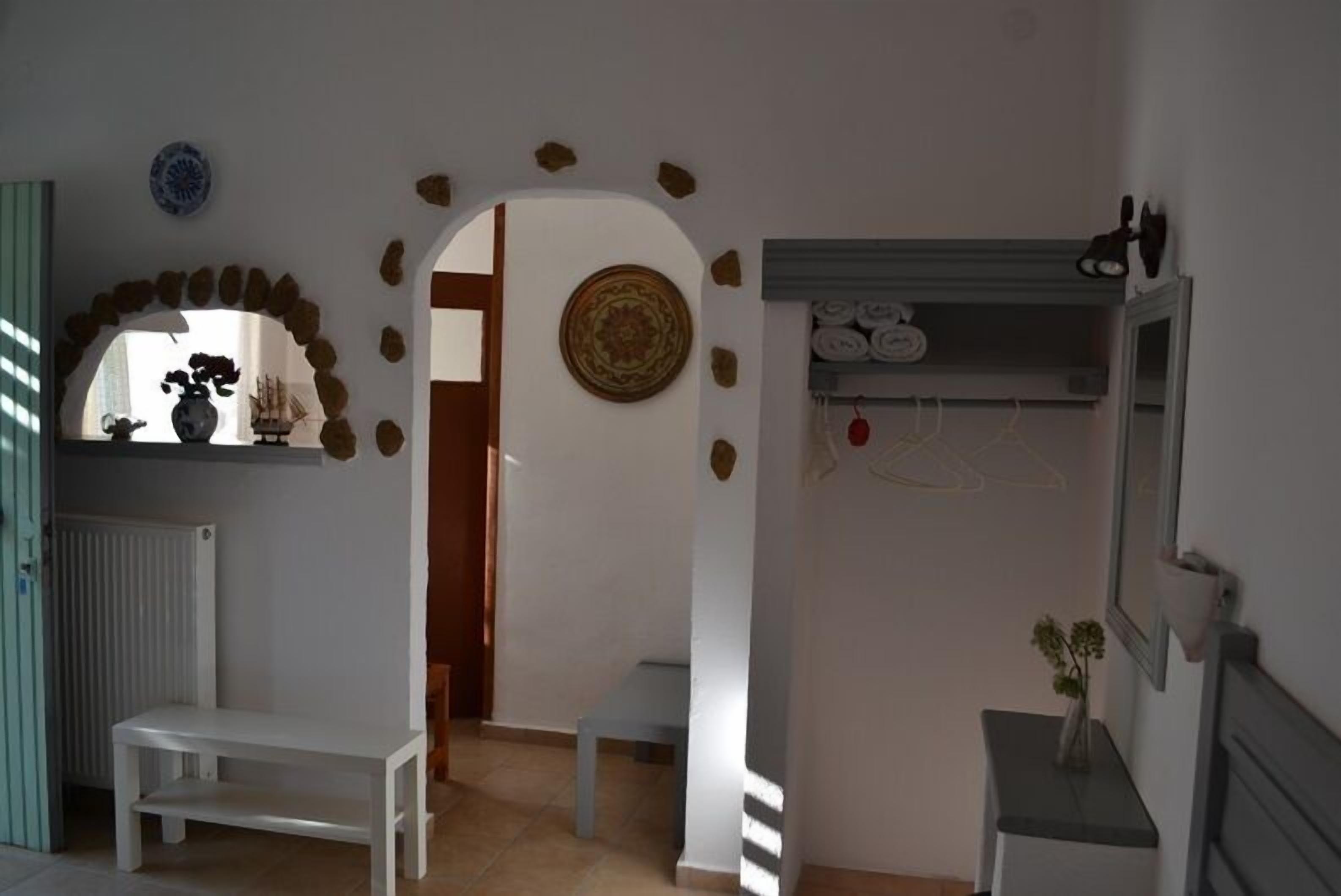 A room with a white bench, a small table, a mirror, and a shelf with folded towels.