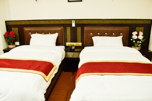 A hotel room with two beds, each with a red and white bedspread, a brown headboard, and a nightstand with a lamp and a phone. - Mandala Hotel Pvt.Ltd. (Kathmandu)
