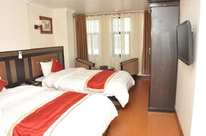 A hotel room with two beds, a flat-screen TV, a desk, and a window with curtains. - Mandala Hotel Pvt.Ltd. (Kathmandu)