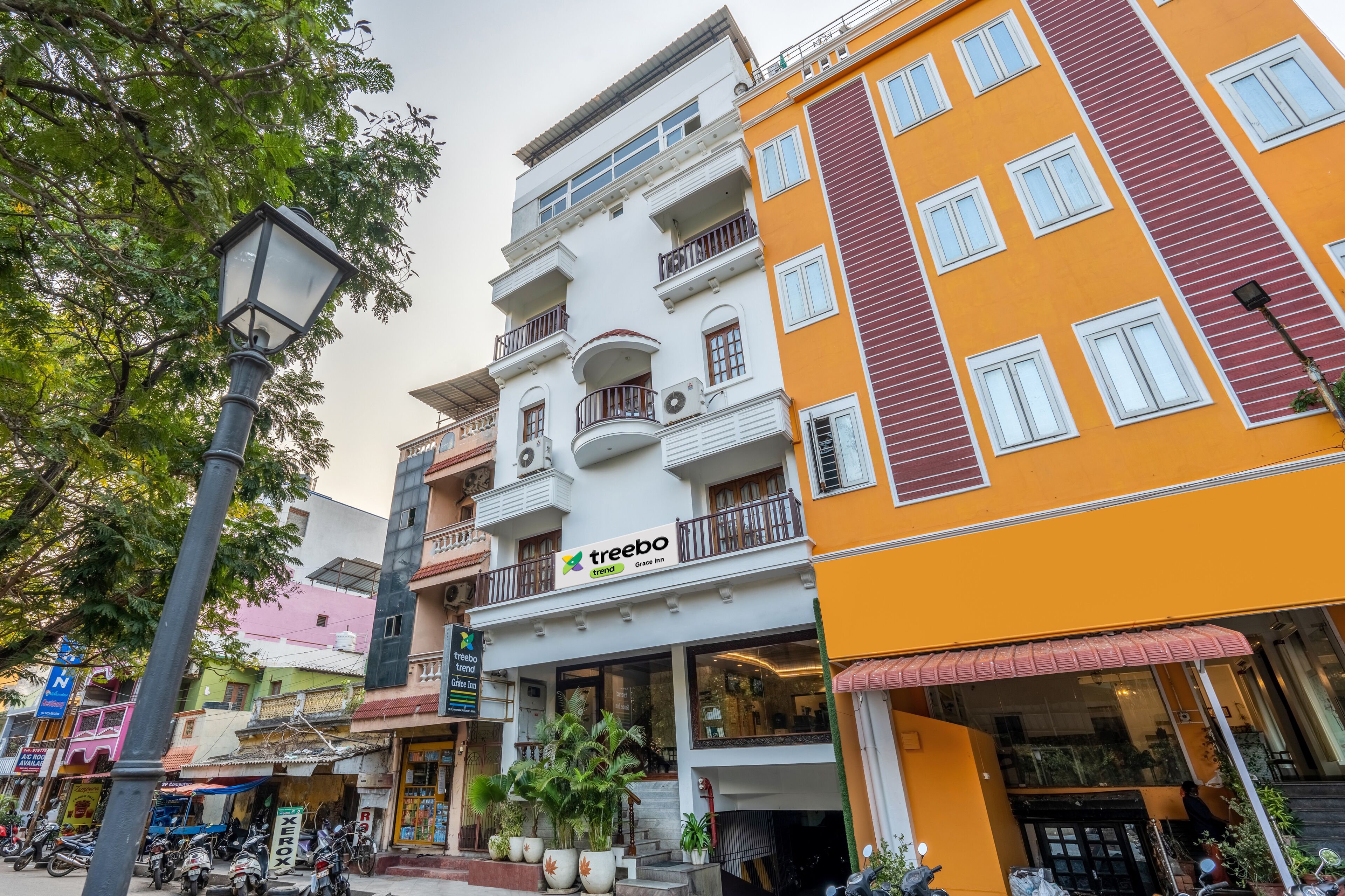 Un immeuble à plusieurs étages, avec une enseigne « Treebo », des balcons et un auvent rouge.