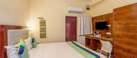 Una habitación de hotel con cama, escritorio, televisor y armario.