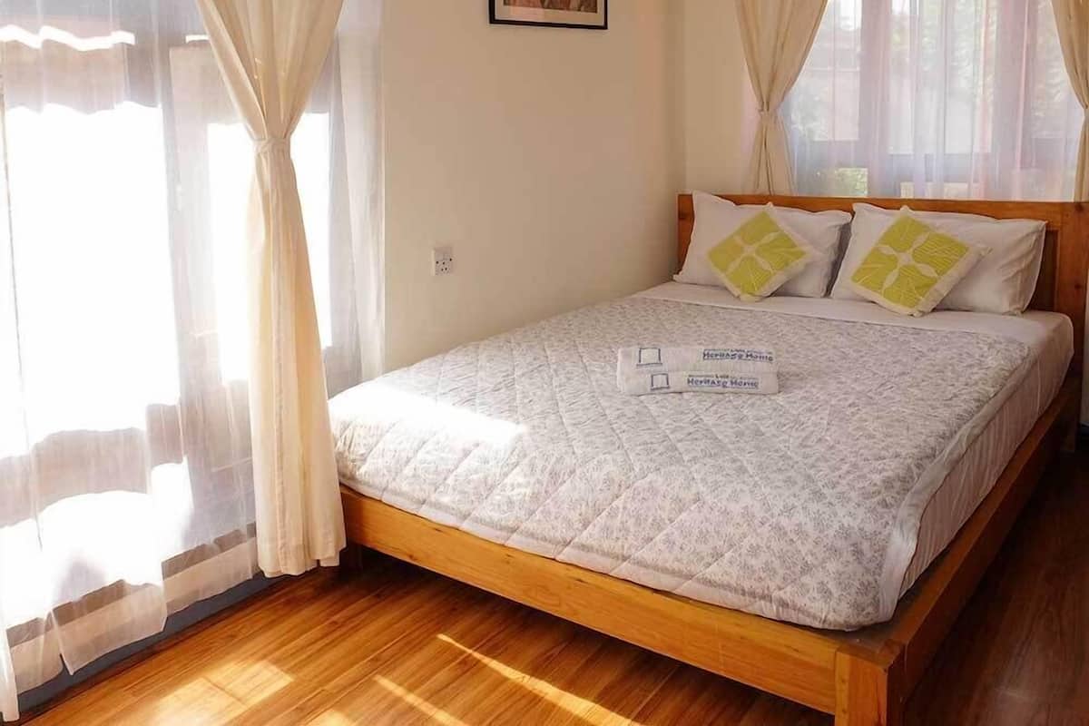 Una cama bien hecha con un edredón acolchado, dos almohadas y una toalla doblada.